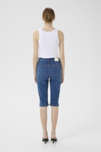 Denim capri hlače v temno modrem pranju, z srednjim pasom, zasnovo petih žepov in zvitimi hlačnicami. Opremljene z majhno etiketo na zadnji strani.