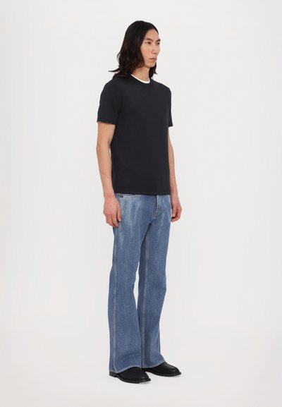 Svart kortermet t-skjorte med hvit krage, kombinert med lyseblå vide jeans. Antrekket har en avslappet passform og glatte teksturer.