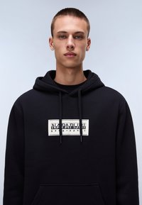 Black hooded sweatshirt made of cotton, featuring a front pocket and a large graphic logo in white, with drawstrings and a soft texture.