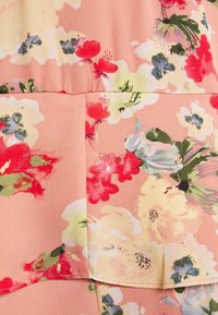 Květnatý materiál s pastelově růžovým pozadím a vícebarevnými květy v červené, žluté, modré a zelené. Hladká textura s jemným povrchem.