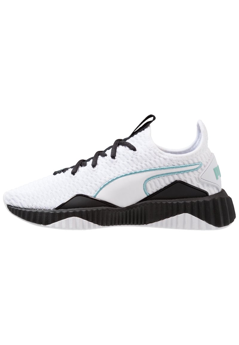 Scarpa sportiva bianca con tomaia in mesh texturizzato, suola in gomma nera e dettagli turchesi. Presenta un collare imbottito e un sistema di lacci.