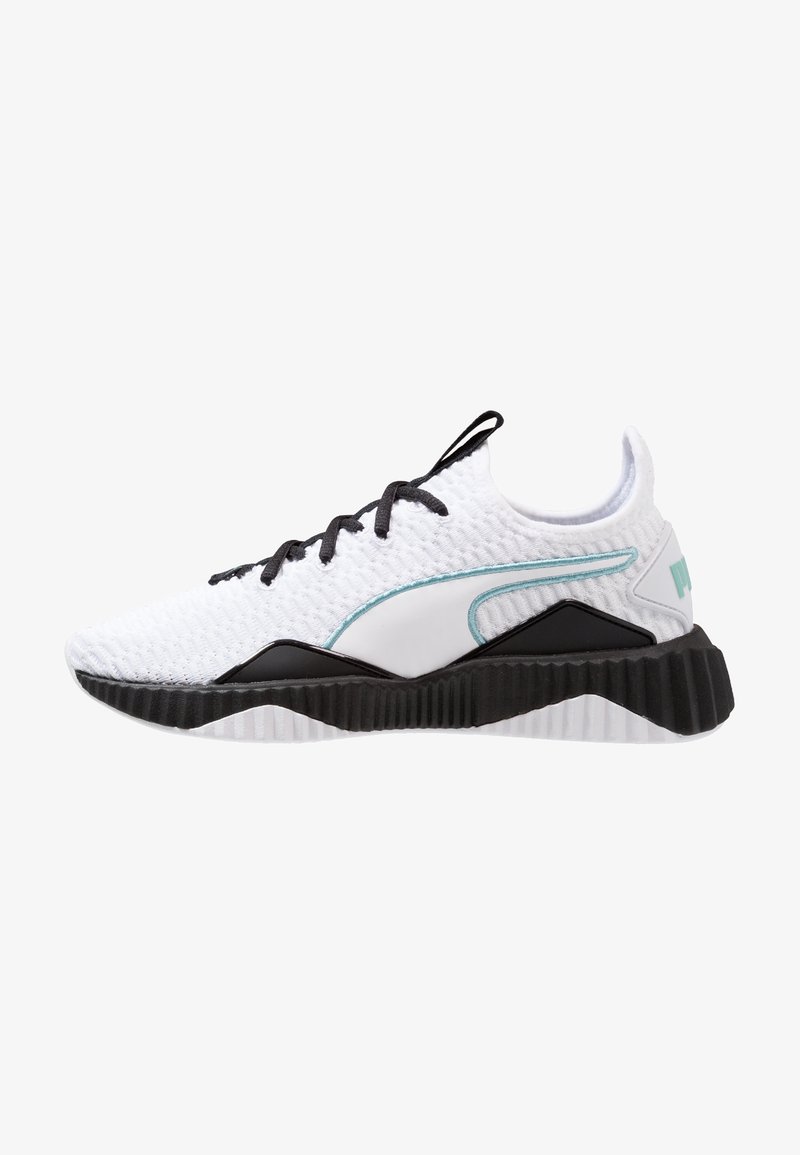 Scarpa sportiva bianca con tomaia in mesh texturizzato, suola in gomma nera e dettagli turchesi. Presenta un collare imbottito e un sistema di lacci.