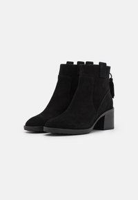 Svarta mockakängor med rund tå, kraftig klack, sidodetaljer och öglor högst upp för enkel påtagning.