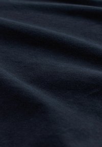 Marineblaues Baumwollgewebe mit glatter Textur und leichtem Glanz, das subtile Falten und einen weichen Fall zeigt.