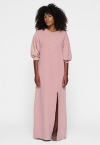 Pastelroze, maxi-jurk met korte pofmouwen, ronde hals en een split aan de voorkant. Gemaakt van zachte stof, met een casual ontwerp.