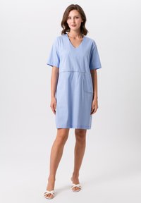 Himmelblaues Baumwollkleid mit kurzen Ärmeln, V-Ausschnitt und einer vorderen Tasche. Verfügt über subtile Stickdetails und eine gerade Silhouette.