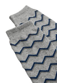 Calcetines grises con patrón de zigzag azul, con puño acanalado y una textura suave. El diseño presenta colores contrastantes y un motivo geométrico.