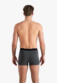 Boxer-culottes gris avec une ceinture élastique noire. Le tissu semble lisse et ajusté, présentant une longueur mi-cuisse et un design sans couture à l'arrière.