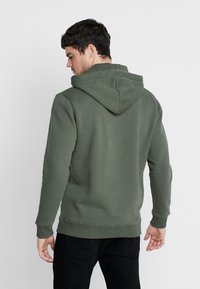 Groene hoodie van een katoenmengsel, met een kangoeroezak, ribgebreide manchetten en een verstelbare trekkoordkap. Slank figura.