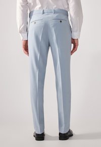 Pantalones de traje azul claro con un ajuste a medida, que cuentan con dos bolsillos traseros con botones dorados y una textura de tela suave.