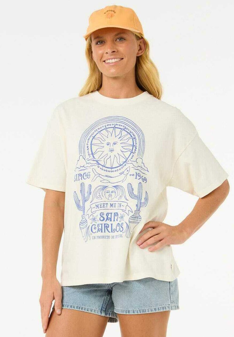 Cremfarbener, übergroßer T-Shirt mit blauem Grafikdesign eines Sonnen, Wolken und Kakteen, kombiniert mit Jeansshorts und einer orangefarbenen Mütze.