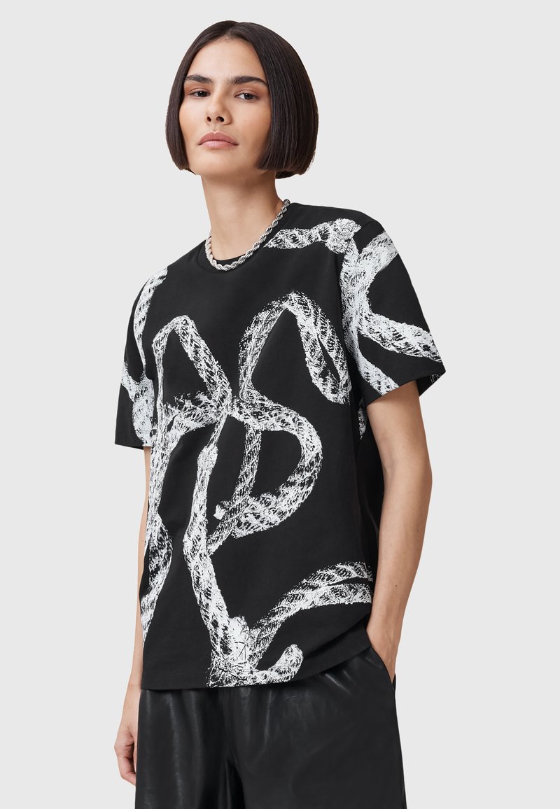 Svart bomull t-shirt med en djärv vit abstrakt design som liknar ihopflätade rep, med avslappnad passform och rund halsringning.