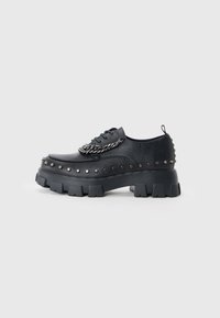 Pantofi cu platformă din piele neagră, cu accente cu �ținte și detalii cu lanț. Dispun de talpă groasă și robustă și un design cu vârf rotund.