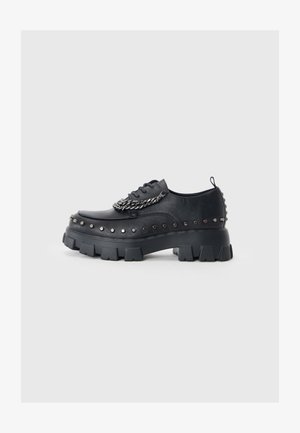 Zwarte lederen platform schoenen met gestofte accenten en een kettingdetail. Heeft dikke, robuuste zolen en een ronde neusontwerp.