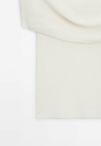 Tissu en maille côtelée de couleur crème, plié de manière lisse, montrant la texture et de fines lignes verticales sur une surface de matériau doux.