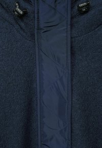 Navy hooded jacket with a textured fleece body and a smooth, quilted nylon front panel. Features adjustable drawstring at the neck.