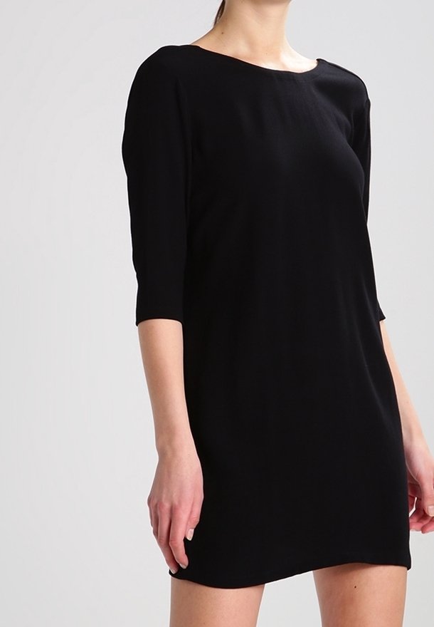 Svart klänning med trekvartsärmar, rund halsringning och en lös passform. Tillverkad av mjukt, slätt tyg utan synliga mönster eller dekorationer.