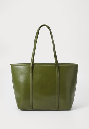 Sac cabas en cuir vert olive avec deux longues anses et une finition lisse légèrement brillante sur un fond uni.