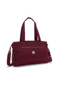 Sac bourgogne en tissu текстuré, avec deux poignées, une bandoulière ajustable, une poche zippée à l'avant et un détail de logo circulaire.
