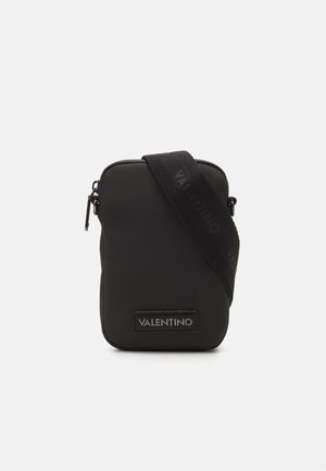 Black nylon crossbody bag with a textured finish, zipper closure, and a shoulder strap featuring the logo. Rectangular shape with a logo patch.