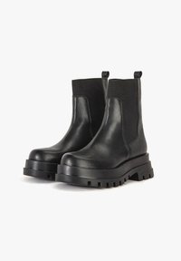 Svarta läderankleboots med elastiska sidopaneler, kraftiga sulor och dragremmar. Slät yta med texturerad gummisula och sömnadsdetaljer.