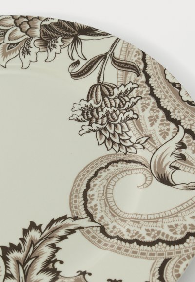 Assiette en porcelaine avec des motifs floraux et cachemire détaillés en beige et marron le long du bord sur fond blanc.