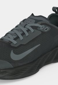 Μαύρο και σκούρο γκρι παπούτσι τρεξίματος Nike με γκρι κορδόνια, λογότυπο swoosh στο πλευρό και υφασμένη λεπτομέρεια στην σόλα.