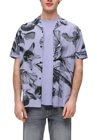 Koszula z krótkim rękawem w jasnofioletowym kolorze z czarnymi abstrakcyjnymi wzorami kwiatowymi. Noszona na dopasowanej koszulce z okrągłym dekoltem, zestawiona z jasnymi dżinsami.