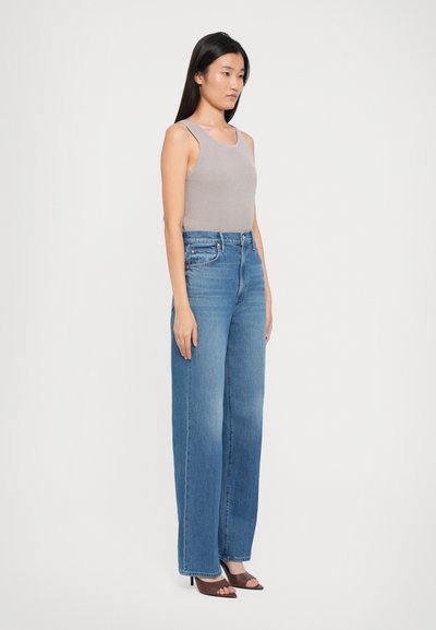 Light grey ribbed tank top paired with blue wide-leg denim jeans, featuring a high waist and straight-cut legs, worn with black heeled sandals.