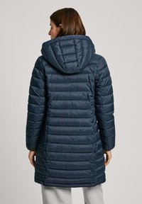 Manteau rembourré marine avec capuche, présentant un design matelassé et une texture côtelée. Longueur genou, avec des manches longues et une fermeture éclair.