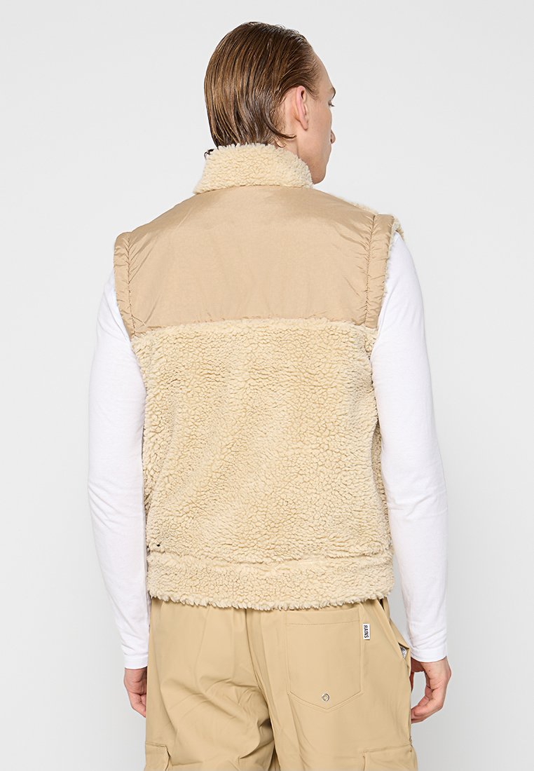 Gilet senza maniche color khaki con un morbido retro in pile testurizzato e parte anteriore liscia, dotato di un colletto alto e senza chiusure visibili.
