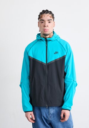 Heren hoodie-jack met een teal bovenstuk en een zwart onderstuk, gemaakt van lichtgewicht stof met een ritsluiting en zijzakken.