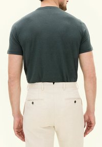 Mörkgrå kortärmad T-shirt med rundad skärning, kombinerad med ljus beige strukturerade byxor med bakfickor och knappdetaljer.