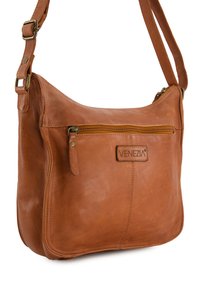 Tan leather shoulder bag with rounded shape, front zipper pocket, and embossed logo. Adjustable strap and smooth texture.