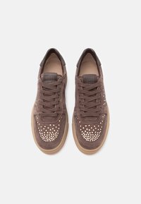 Καφέ σουέντ αθλητικά παπούτσια με διάτρητες λεπτομέρειες στη μύτη, στρογγυλά κορδόνια και σόλα από καουτσούκ gum. Μινιμαλιστικός σχεδιασμός με λογότυπα.