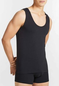 Top in cotone nero senza maniche con scollo a barca. Il tessuto è liscio con una vestibilità aderente e bordi senza cuciture.