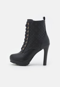 Botines negros hasta el tobillo con tacón alto, con un panel lateral texturizado y ojales en tono dorado, fabricados con materiales sintéticos.