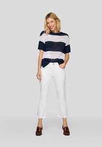 Gestreiftes Strickoberteil in Marineblau und Weiß mit lockerer Passform und kurzen Ärmeln, kombiniert mit weißen, knöchellangen Hosen und braunen Mokassins.