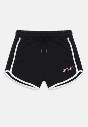 Črne športne kratke hlače z belo obrobo, elastičnim pasom z vrvico za zategovanje in roza logotipom "GUESS" na spodnjem desnem delu noge.