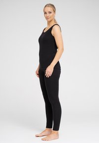Sort tanktop og leggings sæt lavet af blødt stof, med et tætsiddende design, scoop-halsudskæring og uden synlige mønstre eller accenter.