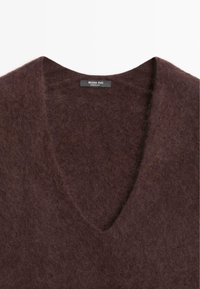 Maglione v-neck in lana marrone con una consistenza morbida e pelosa. L'etichetta riporta "Massimo Dutti". Il design presenta un ampio scollo rilassato.
