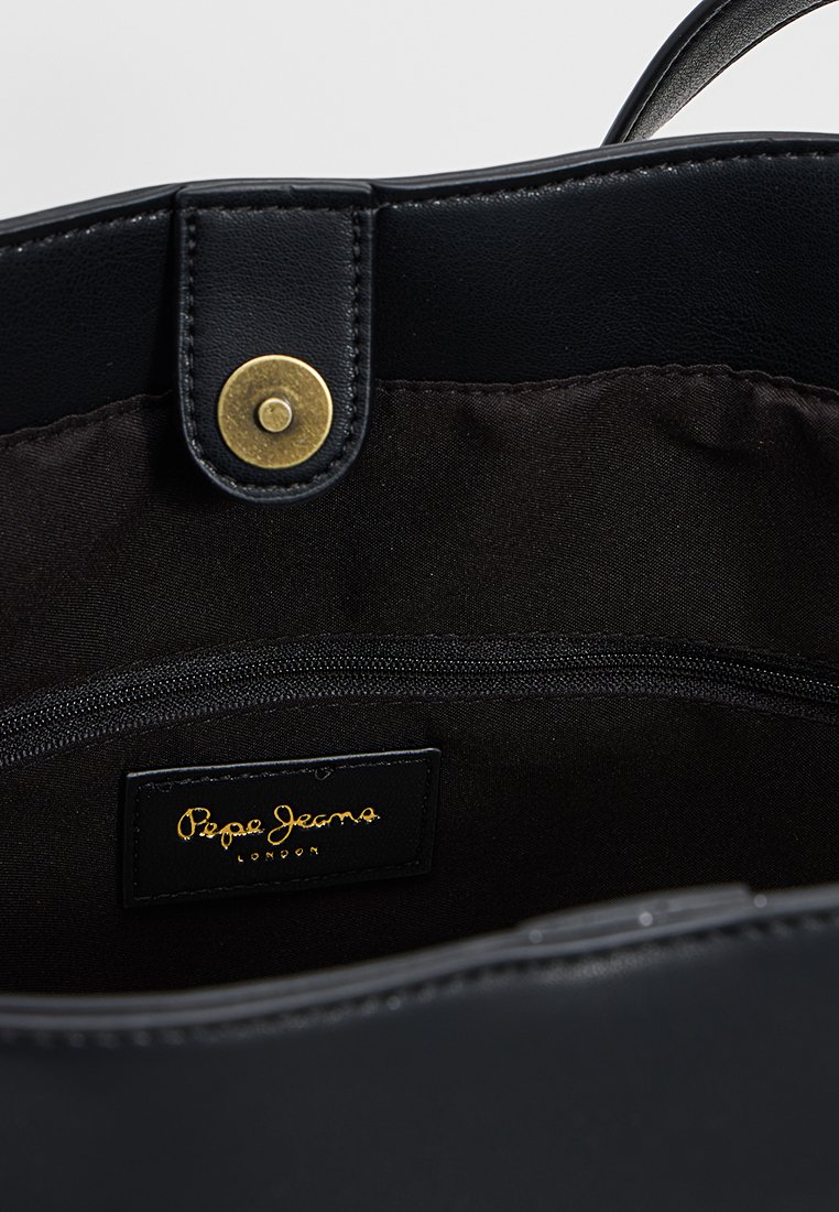 Vista interior de un bolso de cuero negro con un botón de presión dorado, forro de tela y una etiqueta negra marcada "Pepe Jeans London."