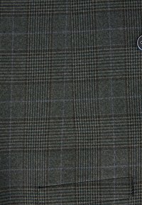 Tissu en laine avec un motif à carreaux vert foncé et marron, présentant de fines lignes bleues formant un design en damier et une finition texturée.