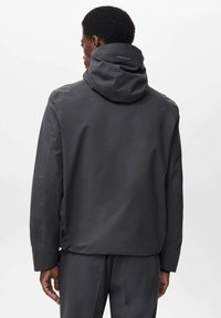 Jachetă impermeabilă de culoare gri închis, cu glugă. Are un design minimalist, textură fină și detalii branduite discret pe guler și spate.