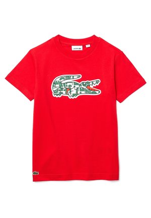 Camiseta de algodón roja con un logo de cocodrilo verde con diseño estampado. Cuello redondo clásico, mangas cortas y marca Lacoste.