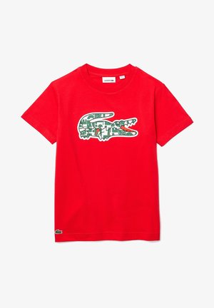 Maglietta rossa in cotone con logo coccodrillo verde dal design a motivi. Classico scollo rotondo, maniche corte e marchio Lacoste.