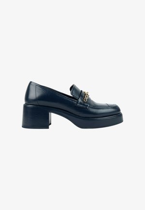 Mocassin en cuir noir avec talon bloc et détail d'une chaîne dorée sur le dessus, vu de profil sur un fond blanc uni.