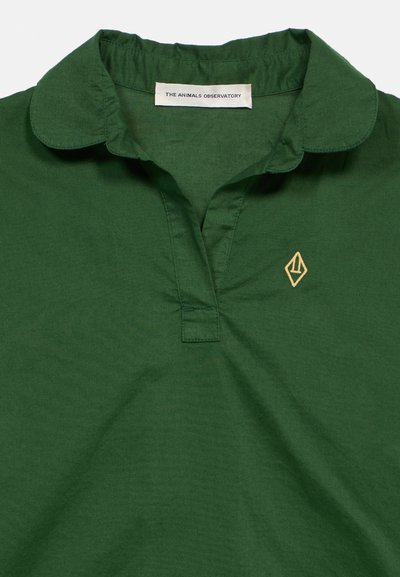 Πράσινο πουκάμισο με γιακά, κοντή πατιλέτα, κεντημένο κίτρινο γεωμετρικό λογότυπο στο στήθος και ετικέτα "THE ANIMALS OBSERVATORY" στο εσωτερικό του γιακά.