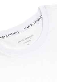Biała bawełniana koszulka z okrągłym dekoltem i ribbowym kołnierzykiem. Metka wewnątrz mówi "PAKO LORENTE UNDERWEAR M." Miękka tekstura, bez wzorów.