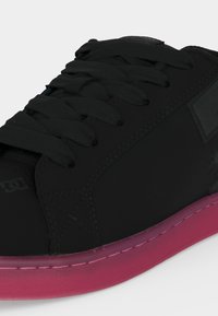 Μαύρο χαμηλό sneaker με μαύρα κορδόνια και ροζ σόλα, με ραμμένα πάνελ και διακριτικό λογότυπο της μάρκας στο πλάι.